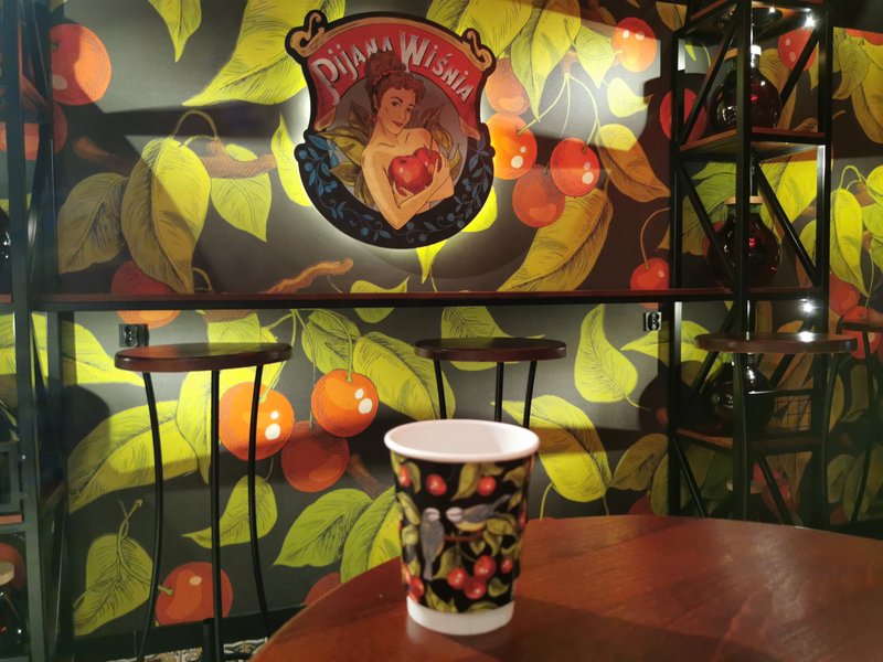Pijana Wisnia interior with view of painted logo, woman holding cherries